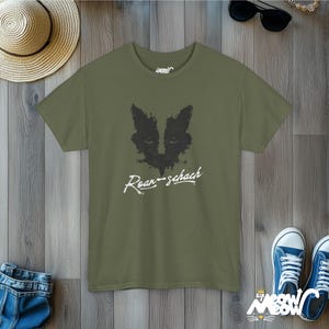 May include: A green t-shirt with a black and white graphic of a cat's face and the text "Roar-schach" printed on the front.