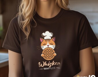 May include: A brown t-shirt with a cartoon cat wearing a chef's hat and holding a waffle. The text "Whiskern Waffles" is printed below the cat.