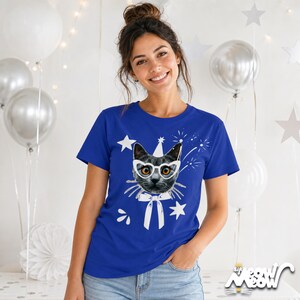 Puede incluir: Camiseta azul real con un gato con gafas, un gorro de fiesta y una pajarita. Estrellas blancas y fuegos artificiales rodean el gr&aacute;fico del gato. El texto "sip meow meow" est&aacute; en la parte inferior derecha.