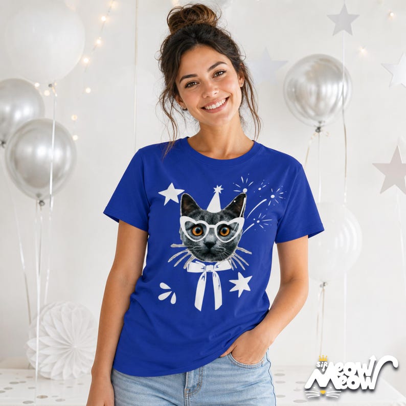 Puede incluir: Camiseta azul real con un gato con gafas, un gorro de fiesta y una pajarita. Estrellas blancas y fuegos artificiales rodean el gr&aacute;fico del gato. El texto "sip meow meow" est&aacute; en la parte inferior derecha.