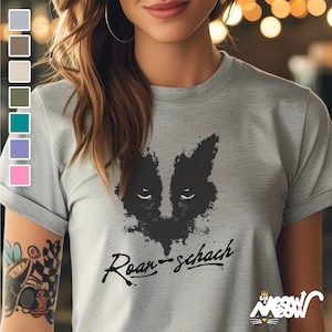 May include: A light gray t-shirt with a black and white graphic of a cat's face with the text "Roar-schach" printed on the front.