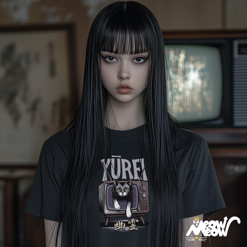 Op de afbeelding: Een vrouw met lang zwart haar draagt een zwart T-shirt met een afbeelding van een kat in een vintage televisie. De tekst op het shirt luidt "YUREX" en "地霊".