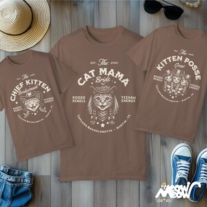 May include: Three brown t-shirts with cat-themed graphics. One shirt says "Cat Mama Bride," another says "Chief Kitten Bridesmaid," and the third says "Kitten Posse Crew." The shirts have a rodeo theme with the text "Yeehaw Energy" and "Taylor's Bachelorette, Austin, TX."