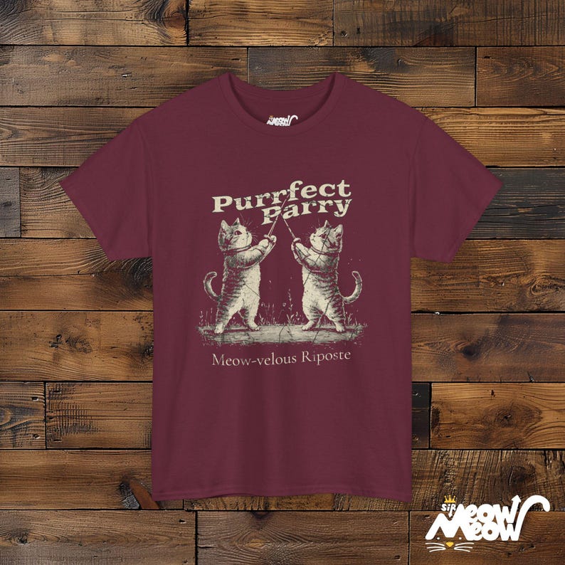 May include: Burgundy t-shirt with a graphic of two cats fencing. The text reads "Purrfect Parry" and "Meow-velous Riposte".
