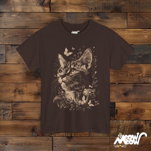 Vintage style t-shirt print of a cat in the woodlands surrounded by wildflowers, mushrooms and butterflies. Chocolate brown tee.