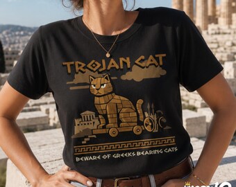 May include: A black short-sleeve t-shirt featuring a graphic of a wooden cat on wheels with the text TROJAN CAT and BEWARE OF GREEKS BEARING CATS. The design includes a stylized ancient building and clouds in shades of brown and tan.