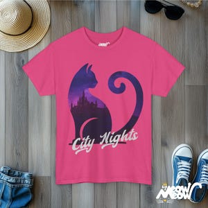 Pode incluir: Camiseta rosa com a silhueta de um gato com um horizonte urbano dentro dele. O texto "City Nights" &eacute; impresso abaixo do gato.