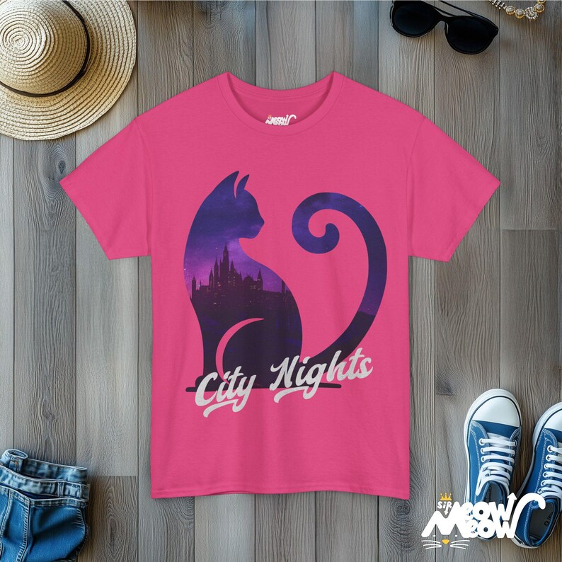 Pode incluir: Camiseta rosa com a silhueta de um gato com um horizonte urbano dentro dele. O texto "City Nights" &eacute; impresso abaixo do gato.