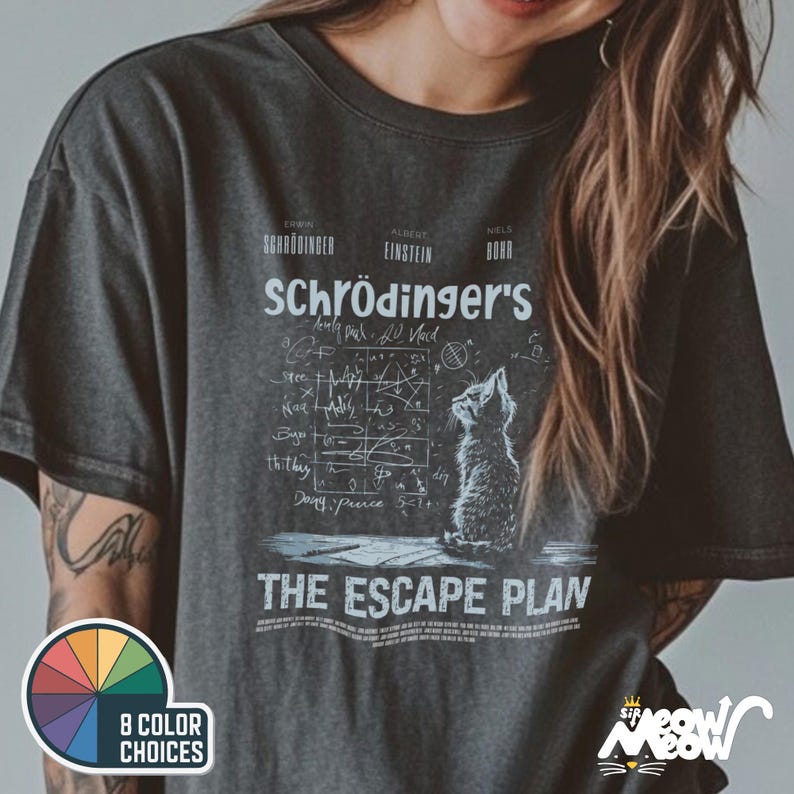 May include: A dark gray t-shirt with a white graphic of a cat looking up at a chalkboard with equations and the text "Schr&ouml;dinger's The Escape Plan".