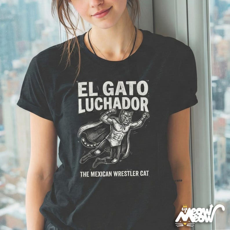 May include: Black t-shirt with the text "EL GATO LUCHADOR" above an illustration of a cat wrestler wearing a mask and cape. Below the illustration is the text "THE MEXICAN WRESTLER CAT".
