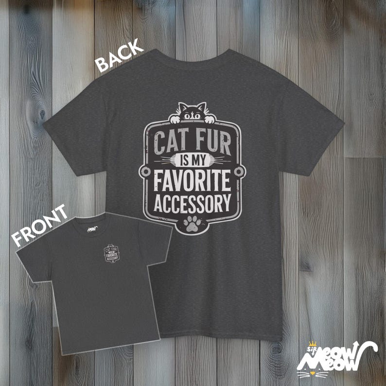 May include: A dark heather grey t-shirt with a vintage-style graphic that says "Cat fur is my favorite accessory". The graphic features a black cat peeking over the top of the text.