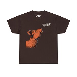 May include: A brown t-shirt with a cartoon illustration of a cow looking up and the text "*MEEOOOW*" printed on the front.