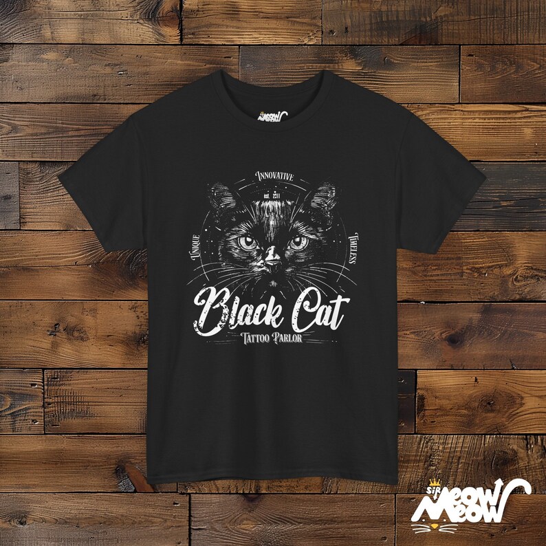 K&ouml;nnte beinhalten: Schwarzes T-Shirt mit einer Illustration einer schwarzen Katze und dem Text "Black Cat Tattoo Parlor" in einer Vintage-Schriftart.