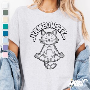 Peut inclure: Un t-shirt gris avec le texte "Nameowste" en contour noir. Une illustration en noir et blanc d'un chat assis en position de yoga est centr&eacute;e sous le texte.