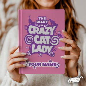 May include: A pink journal with the text "THE DIARY OF A CRAZY CAT LADY" in purple, with a space for a name. The cover features cat silhouettes and star accents. The journal is held by a person.