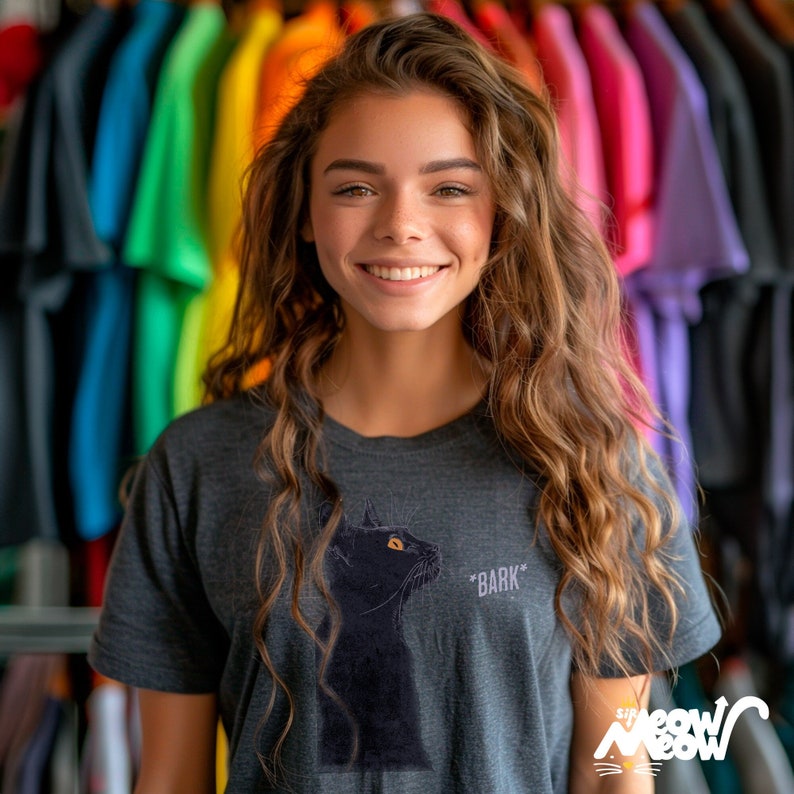 Young woman wearing a dark gray t-shirt with an illustration of a black cat. Beside the cat is the text '* BARK *'