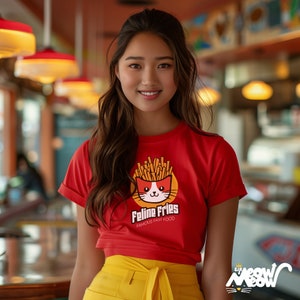 May include: A woman wearing a red t-shirt with a cartoon cat wearing a bowl of french fries on its head. The shirt says "Feline Fries Famous Fast Food".