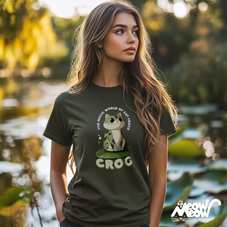 May include: A green t-shirt with a cartoon cat sitting on a lily pad. The text on the shirt reads "The Magic World of Cat Frogs Crog".