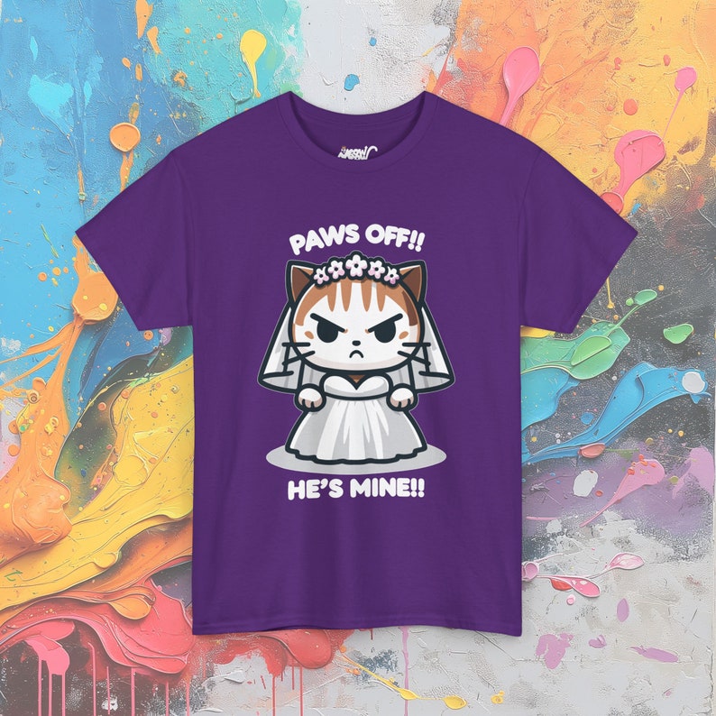 May include: Purple t-shirt with a cartoon cat wearing a white wedding dress and a flower crown. The text "PAWS OFF!! HE'S MINE!!" is printed on the shirt.