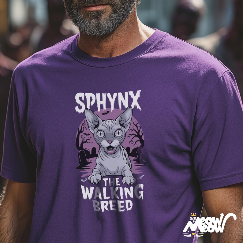 以下が含まれることがあります： 紫色のTシャツ。スフィンクス猫のグラフィックが特徴で、猫の上に「SPHYNX」、下に「THE WALKING BREED」と書かれています。猫は大きな耳を持つグレーで、不気味な墓地のシーンが背景に描かれています。
