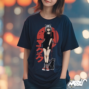 Op de afbeelding: Marineblauw t-shirt met een Japanse anime-stijl illustratie van een meisje met kattenoren, een zwarte kat en een rode zon. De afbeelding bevat Japanse tekst. Het shirt heeft een relaxte pasvorm.