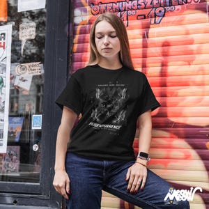 May include: Black t-shirt with a white graphic design featuring scientific symbols and the text "HEISENPURRENCE". The shirt is short-sleeved and has a crew neck. The design includes mathematical symbols and the phrase "TRUTH IS NOT KNOWN".