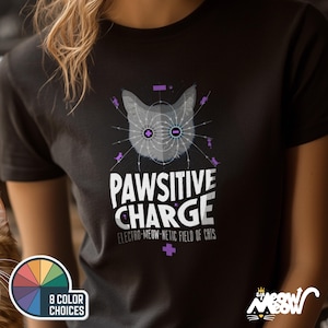 May include: Black t-shirt featuring a graphic of a cat's head with purple lines and the text "PAWSITIVE CHARGE ELECTRO-MEOW-NETIC FIELD OF CATS".
