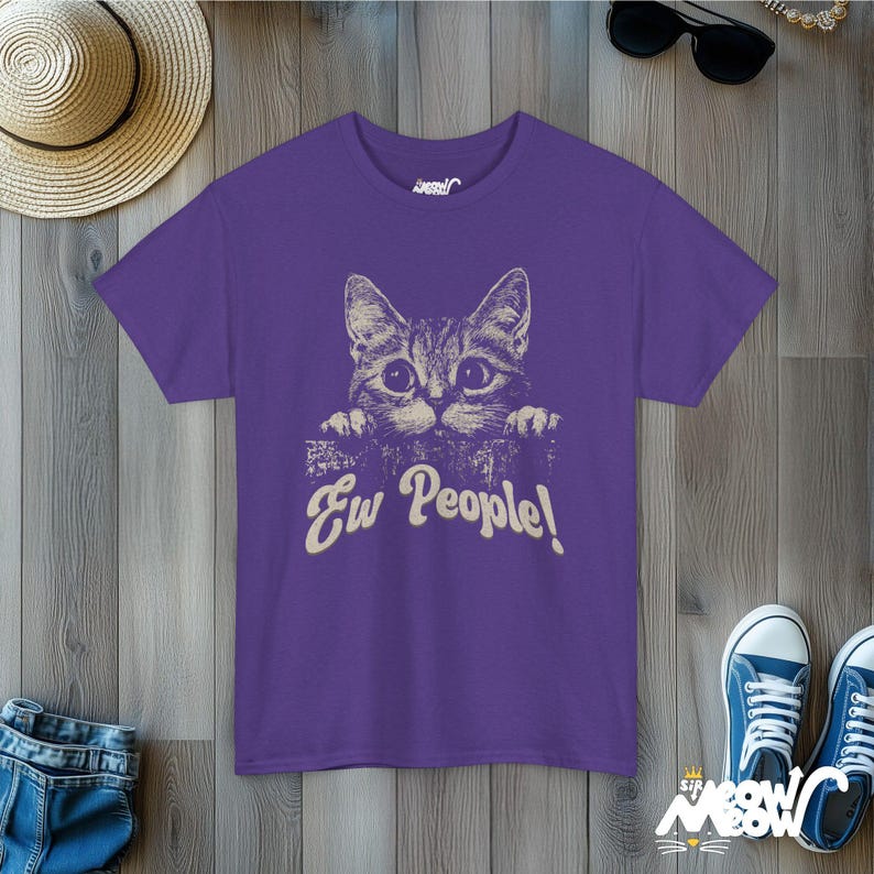 Puede incluir: Camiseta morada con un gr&aacute;fico de un gato asom&aacute;ndose por encima de una superficie y el texto "Ew People!"