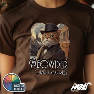 May include: A brown t-shirt with a cat illustration wearing a suit and top hat, with the text "MEOWDER ON THE ORIENT EXPRESS". The design includes a train and a colour palette graphic.