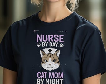 May include: A navy blue t-shirt with a white graphic of a cat wearing a nurse's hat. The text on the graphic reads "Nurse by day, Cat Mom by night".