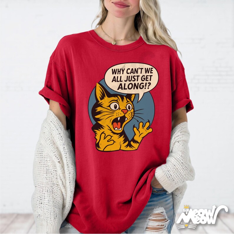May include: Red t-shirt featuring a cartoon cat with an open mouth and the text "WHY CAN'T WE ALL JUST GET ALONG!?" in a speech bubble. The cat is yellow and black, set against a blue circle.