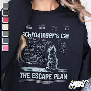 May include: Black sweatshirt with a white graphic of a cat looking up at a chalkboard with equations and the text "Schrödinger's cat" and "The Escape Plan".