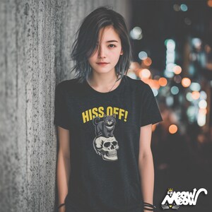 May include: Black t-shirt with the text "HISS OFF!" in yellow, featuring a graphic of a black cat sitting on a skull. The shirt has a crew neck and short sleeves. The brand logo "Sir Meow Meow" is at the bottom right.