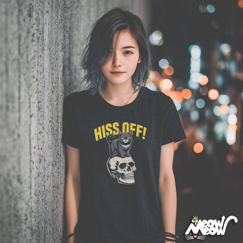 May include: Black t-shirt with the text "HISS OFF!" in yellow, featuring a graphic of a black cat sitting on a skull. The shirt has a crew neck and short sleeves. The brand logo "Sir Meow Meow" is at the bottom right.