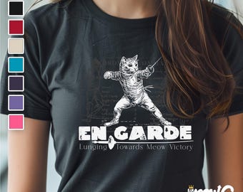 May include: A black t-shirt with a white graphic of a cat fencing. The text "En Garde" is below the cat, and the text "Lunging Towards Meow Victory" is below that.