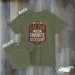 May include: A green t-shirt with a cat peeking out from the top and the text "Cat fur is my favorite accessory". The back of the shirt is plain green.