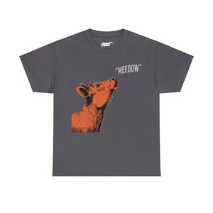May include: A dark gray t-shirt with a cartoon illustration of a cow looking up and the text "*MEEOOOW*" printed on the front.