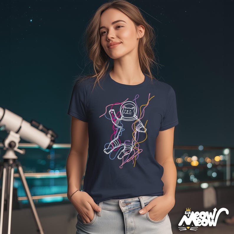 May include: Navy blue t-shirt featuring a white outline of a cat astronaut with colorful lines. The shirt has the text "Sir Meow Meow" in a stylized font. The cat is wearing a space helmet and suit.