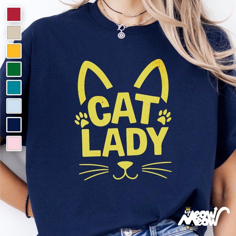 Peut inclure: Un t-shirt bleu marine avec un motif de chat jaune et le texte "Cat Lady".
