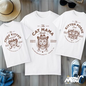 May include: Three white t-shirts with brown graphic designs. One shirt says "Cat Mama Bride," another says "Chief Kitten Bridesmaid," and the third says "Kitten Posse Crew." The shirts have a western theme with cat illustrations.