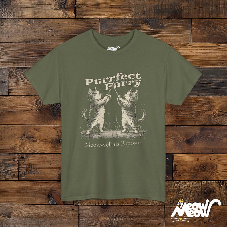 May include: A green t-shirt with a graphic of two cats fencing. The text on the shirt reads "Purrfect Parry Meow-velous Riposte".