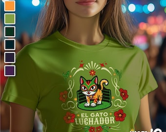 May include: Green t-shirt with a cartoon cat wearing a wrestling mask. The cat is in a wrestling ring with the text "El Gato Luchador" below it. The design is surrounded by flowers and stars.