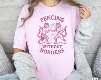 May include: Pink t-shirt with a graphic of two cats fencing with the text "Fencing Without Borders".