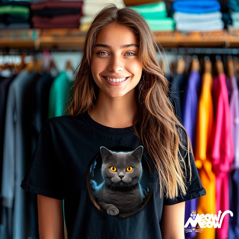 Woman wearing a black t-shirt with a British blue cat appearing to crawl out of a hole in the tee.