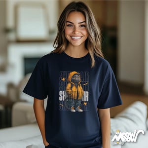 Humanized British Shorthair Cat standing up wearing a yellow hoodie and white and gray sneakers. Behind the cat is a stack of the word "Shorthair". The design appears on a woman wearing a navy tee.