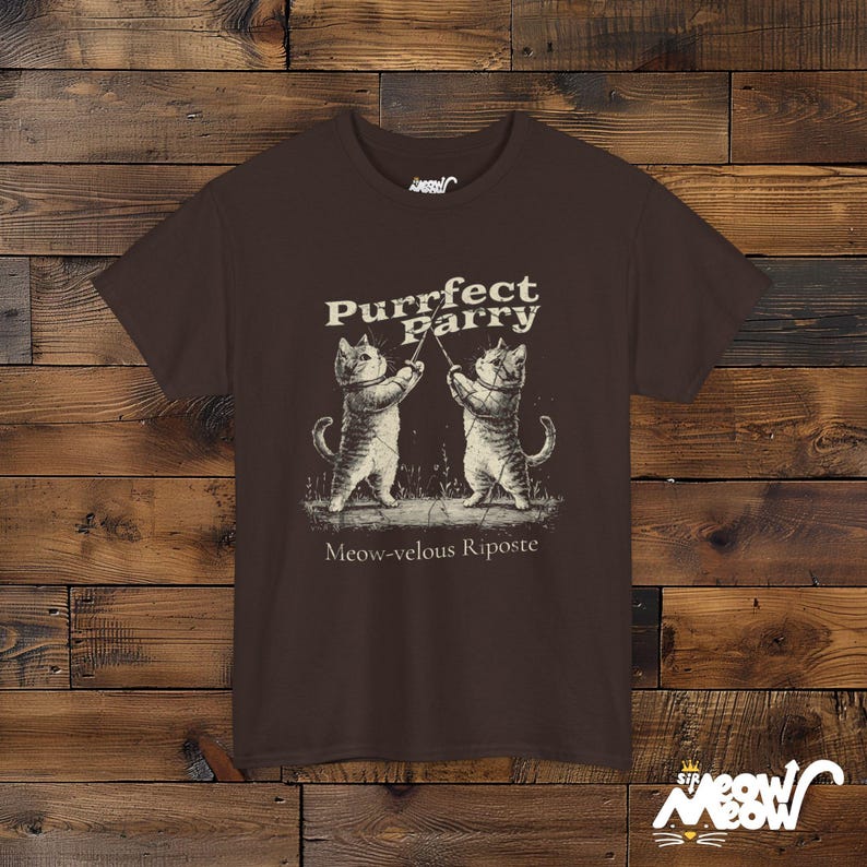 May include: A brown t-shirt with a graphic of two cats fencing. The text on the shirt reads "Purrfect Parry Meow-velous Riposte".