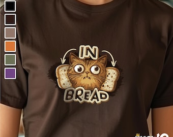 Könnte beinhalten: Ein braunes T-Shirt mit einer Comic-Katze mit großen Augen in zwei Brotscheiben. Der Text "IN BREAD" befindet sich unter der Katze.