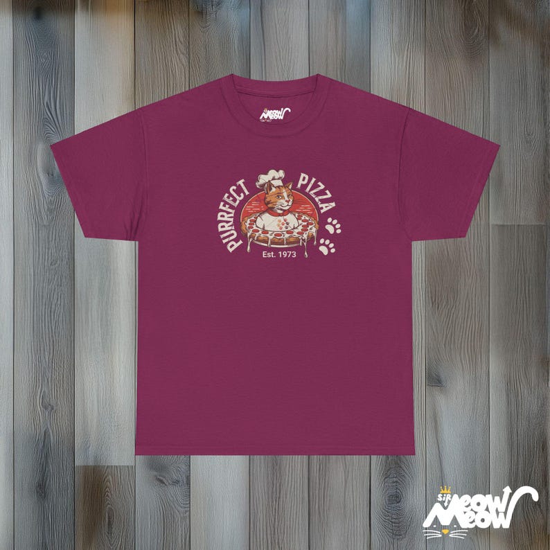 Pode incluir: Uma camiseta vinho com um logotipo de estilo vintage que apresenta um gato usando um chap&eacute;u de cozinheiro e segurando uma pizza. O logotipo diz "Purrfect Pizza" e "Est. 1973".
