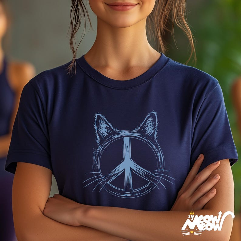 May include: A navy blue t-shirt with a light blue cat head design incorporating a peace symbol. The tee has a crew neck and short sleeves. The text "Sir Meow Meow" is visible at the bottom right.