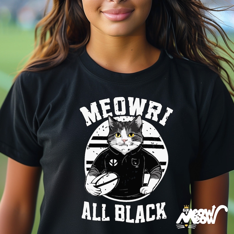 May include: Black t-shirt featuring a white graphic of a cat wearing a black rugby jersey and holding a rugby ball. The text "MEOWRI ALL BLACK" is printed on the shirt.